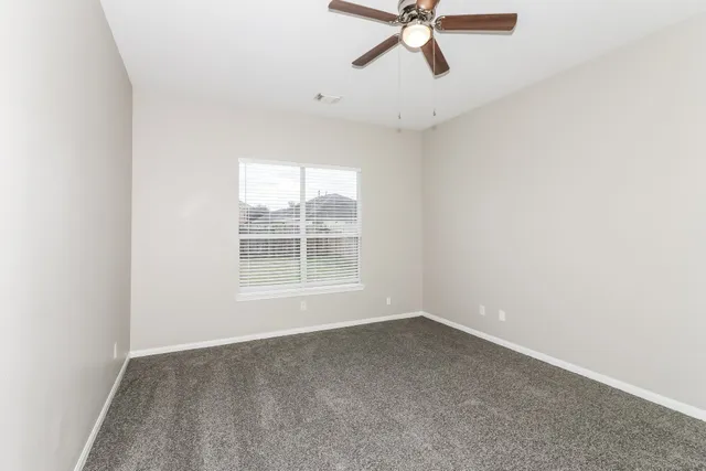 an empty room with a window and a fan
