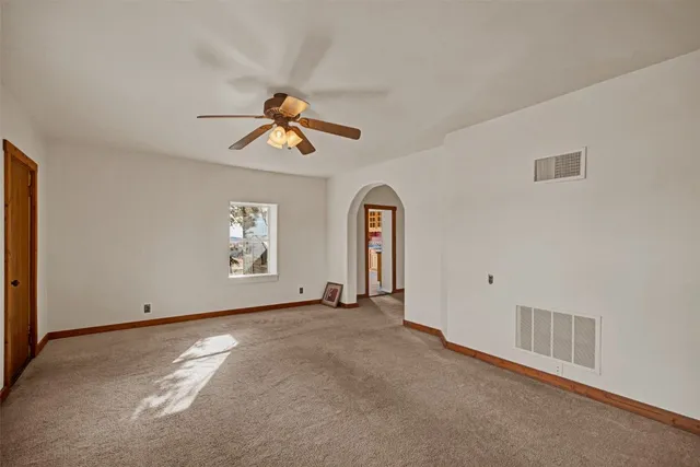 an empty room with chandelier fan and windows