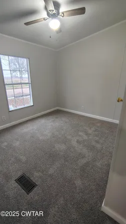 an empty room with windows and chandelier fan