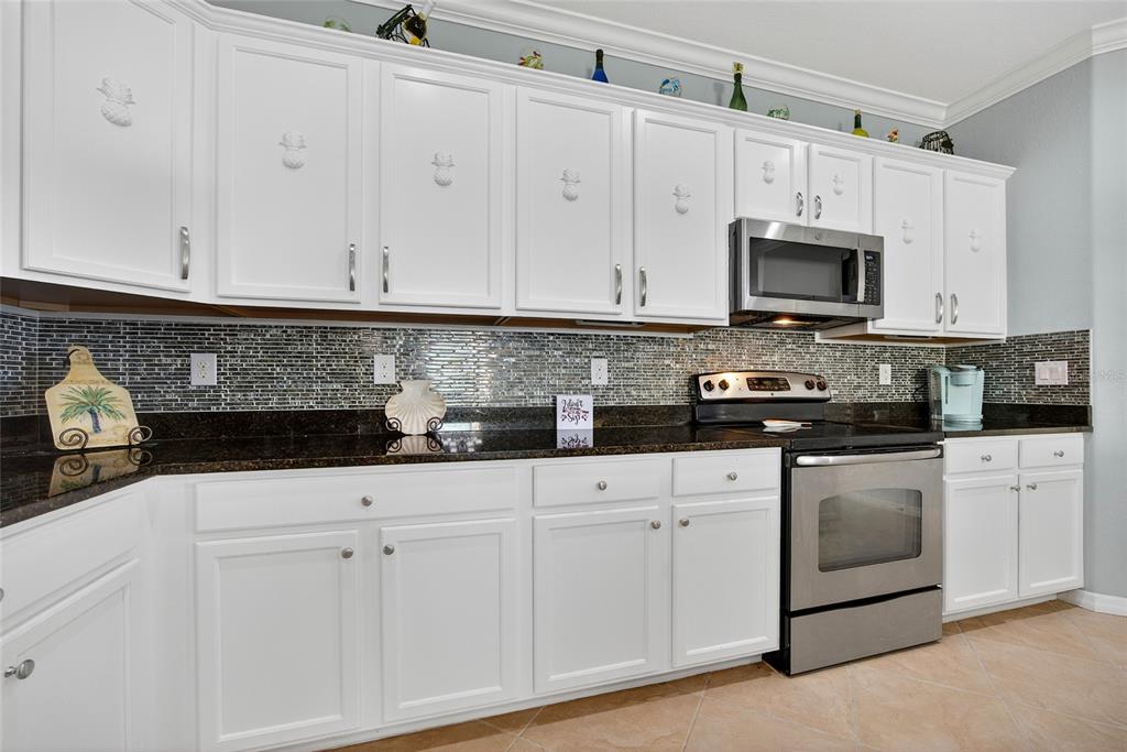 2877 Via Piazza Loop Fort Myers, FL 33905 - Photo 15 of 39 a kitchen with white cabinets and stainless steel appliances