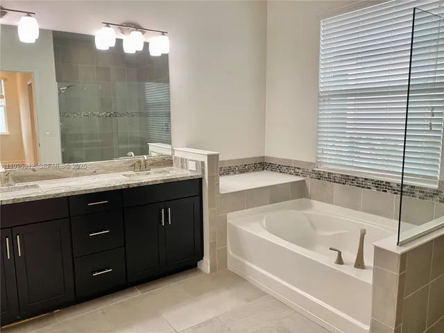 a bathroom with a tub a double vanity sink and mirror