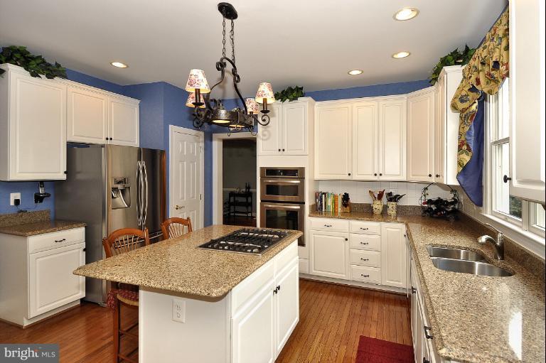 115 Fox Trail Terrace Gaithersburg, MD 20878 - Photo 4 of 22 a kitchen with a stove a sink a refrigerator and white cabinets with wooden floor