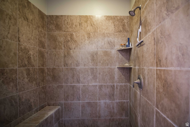 646 East 1400th Street North Mapleton, UT 84664 - Photo 49 of 78 Tiled shower enclosure featuring a built-in bench, two corner shelves, and a bronze-finish shower head with a coordinating control handle