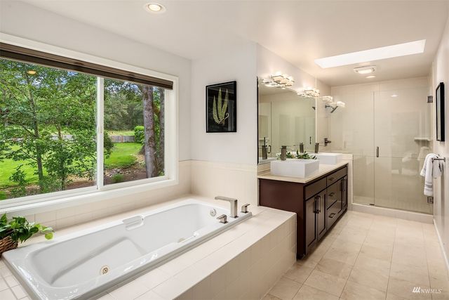 a spacious bathroom with a double vanity sink large mirror and a bathtub