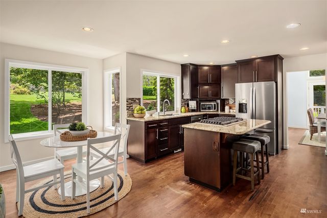 a kitchen with a stove a refrigerator and a dining table with wooden floor