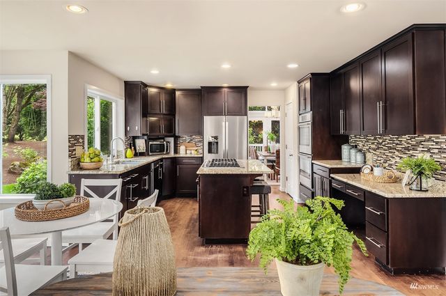 a living room with couches and kitchen view with wooden floor