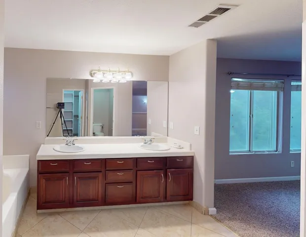 a bathroom with a granite countertop double vanity sink and a mirror