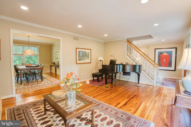 a view of a dining room and livingroom with furniture wooden floor a rug a painting and a chandelier