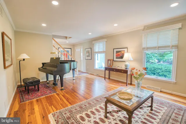 a view of a dining room and livingroom with furniture wooden floor a rug a painting and a chandelier