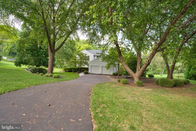 a view of a house with a big yard and large trees