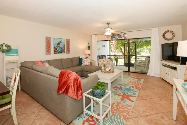 a living room with furniture a flat screen tv and a large window