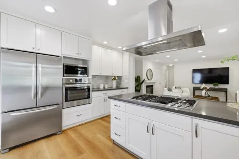 a kitchen with stainless steel appliances kitchen island granite countertop a refrigerator a stove and a sink with cabinets