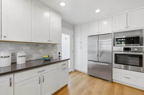 a kitchen with granite countertop white cabinets stainless steel appliances and a counter space