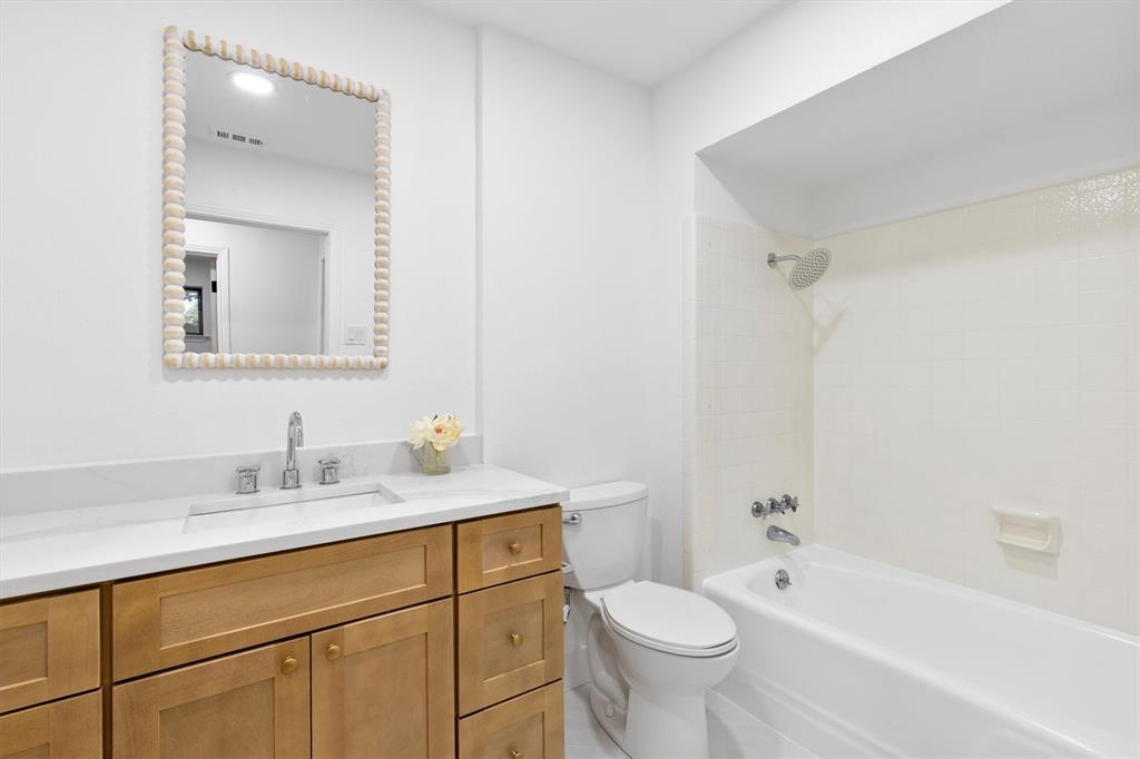 4446 Thunder Road Dallas, TX 75244 - Photo 22 of 30 Bathroom featuring a single vanity with wood-finish cabinetry and a light-colored countertop, an undermount sink, and a framed mirror