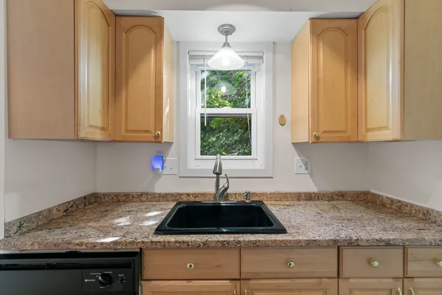 a kitchen with granite countertop a sink a window and cabinets