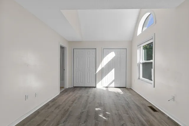 an empty room with wooden floor and windows