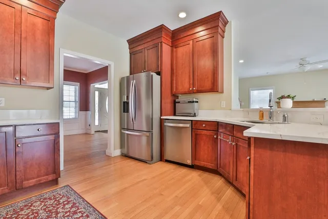 a kitchen with stainless steel appliances granite countertop a refrigerator a sink dishwasher and wooden cabinets with wooden floor