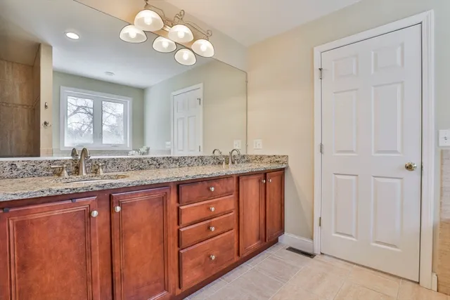 a bathroom with a granite countertop double vanity sink and a mirror