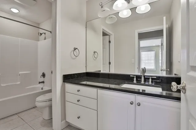 a bathroom with a granite countertop sink a toilet a large mirror a bathtub and shower