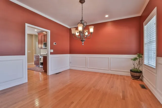 a view of a livingroom with wooden floor a ceiling fan and windows