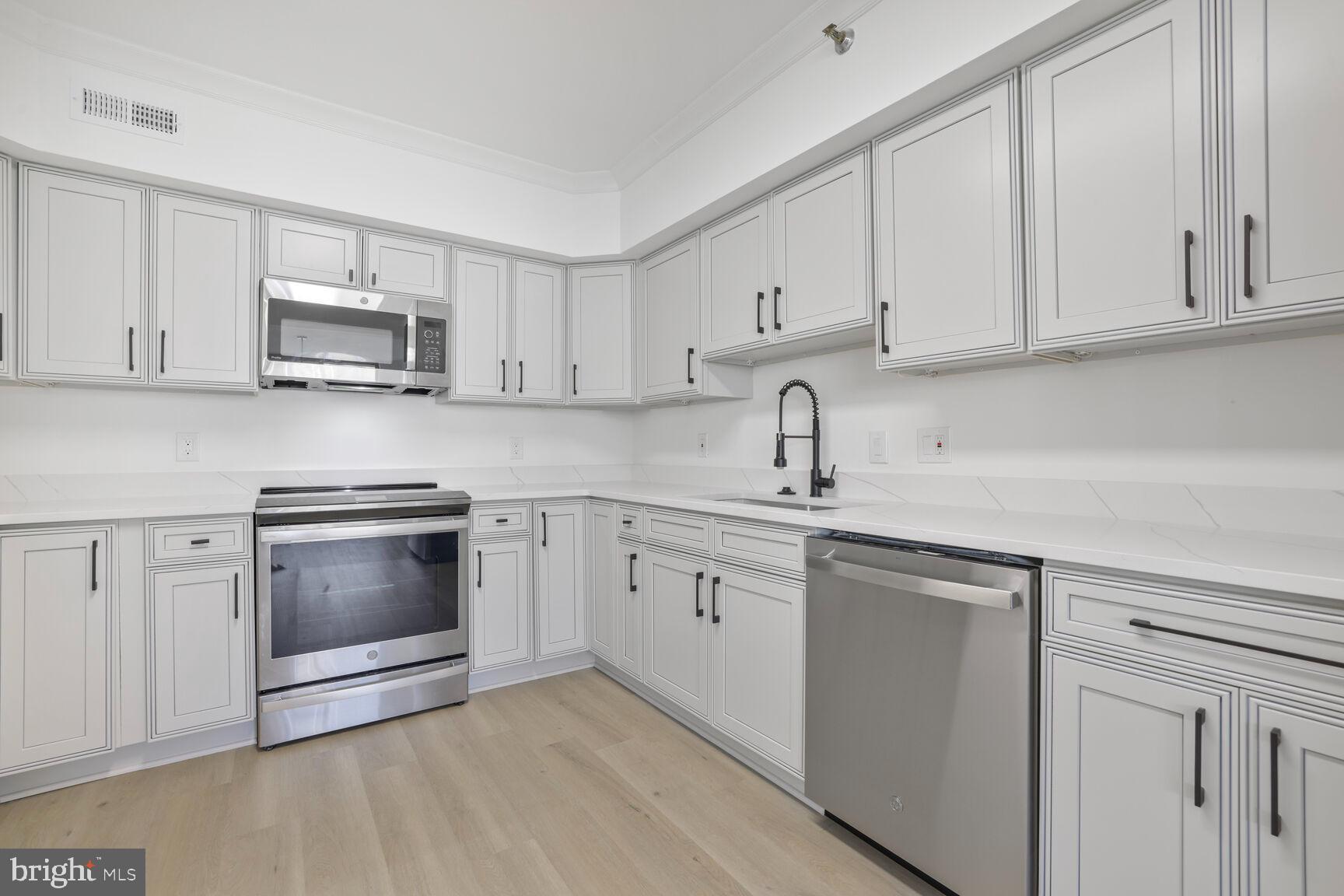 4550 North Park Avenue, Unit 707 Chevy Chase, MD 20815 - Photo 5 of 15 a kitchen with white cabinets stainless steel appliances and sink