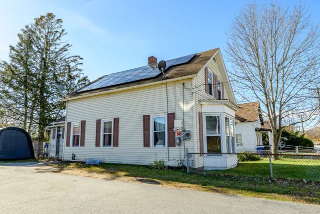 a view of a white house with a large windows and large trees and plants