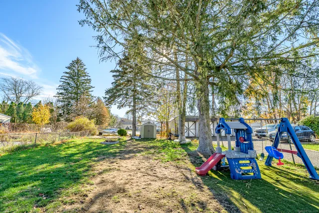 a wooden bench sitting in a yard with large trees