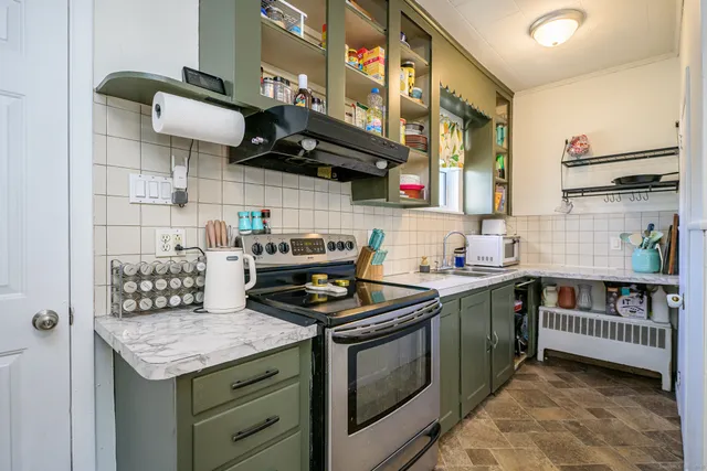 a kitchen with stainless steel appliances granite countertop a stove a sink and a white cabinets