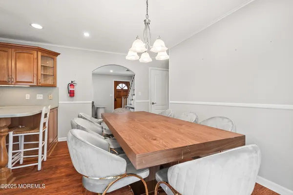 a dining room with wooden floor a chandelier a wooden table and chairs