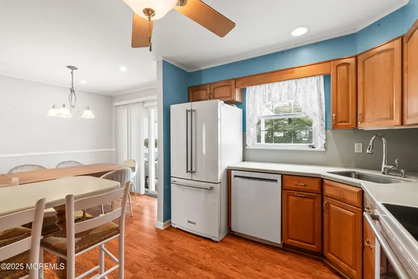 a kitchen with stainless steel appliances granite countertop a refrigerator a sink dishwasher a stove and white countertops with wooden floor