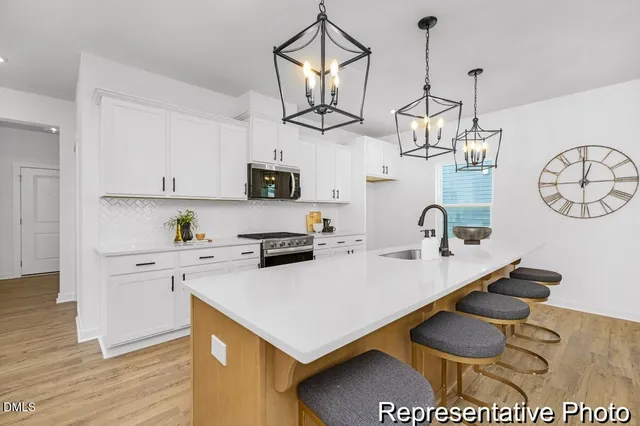 a kitchen with stainless steel appliances a sink a stove a refrigerator and white cabinets