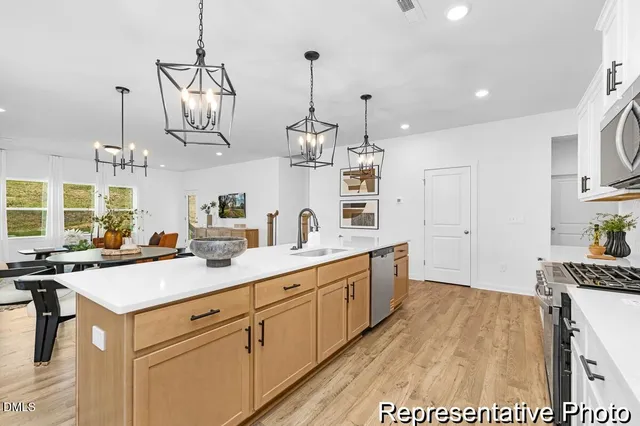 a kitchen with kitchen island granite countertop a sink a counter space appliances and cabinets