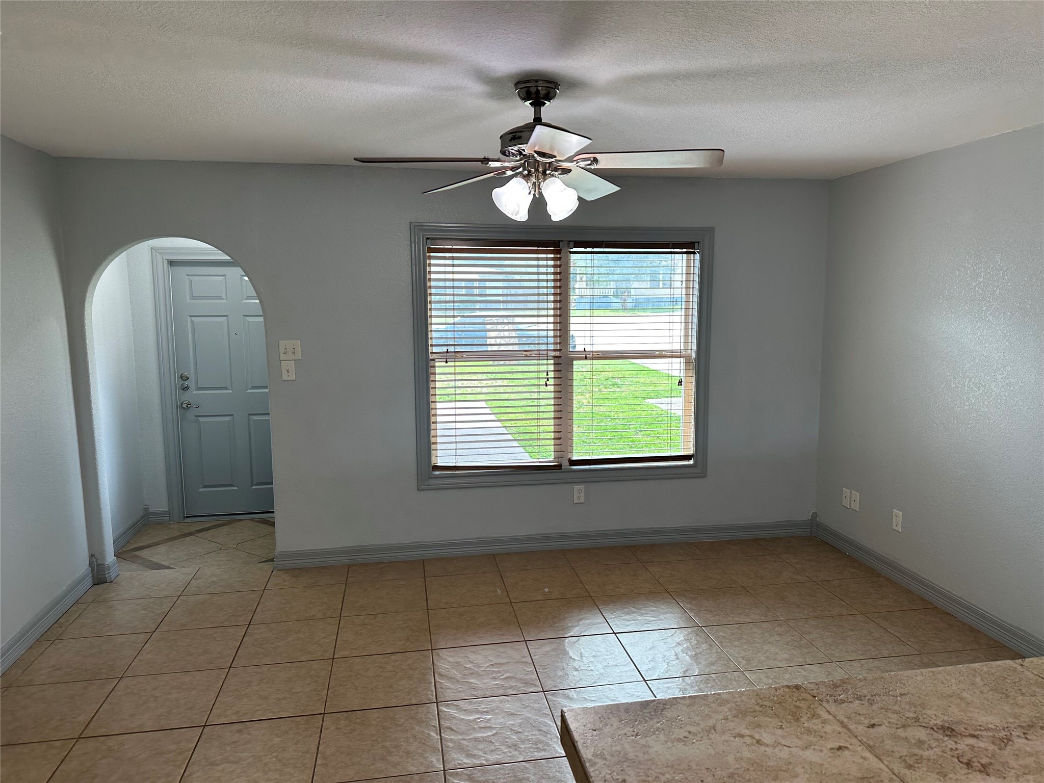 2743 Maple Tree Road, Unit A New Braunfels, TX 78130 - Photo 3 of 18 Empty room featuring arched walkways, a ceiling fan, a textured ceiling, and light tile patterned floors