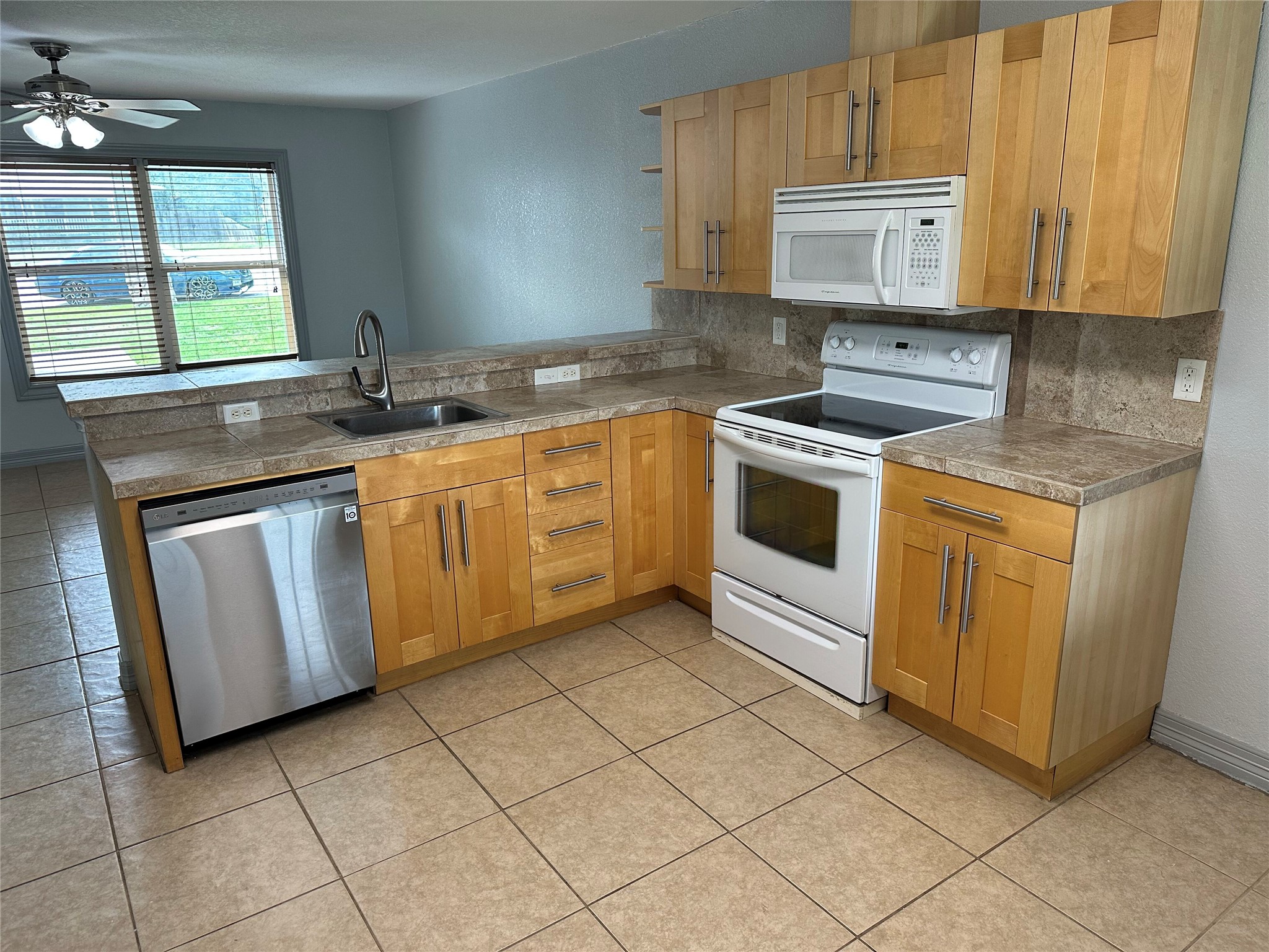 2743 Maple Tree Road, Unit A New Braunfels, TX 78130 - Photo 8 of 18 Kitchen with white appliances, a peninsula, a ceiling fan, and decorative backsplash