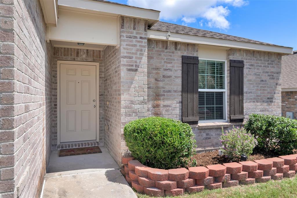 3011 Hickory Ridge Melissa, TX 75454 - Photo 2 of 30 Brick exterior featuring a paneled entry door, covered porch, and a window with dark wood shutters