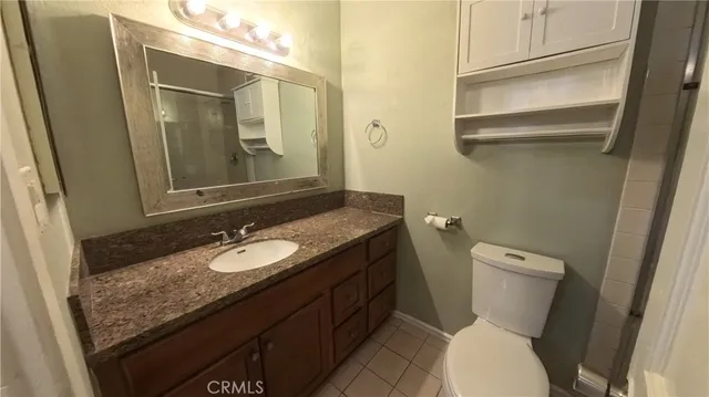 a bathroom with a granite countertop sink toilet and mirror
