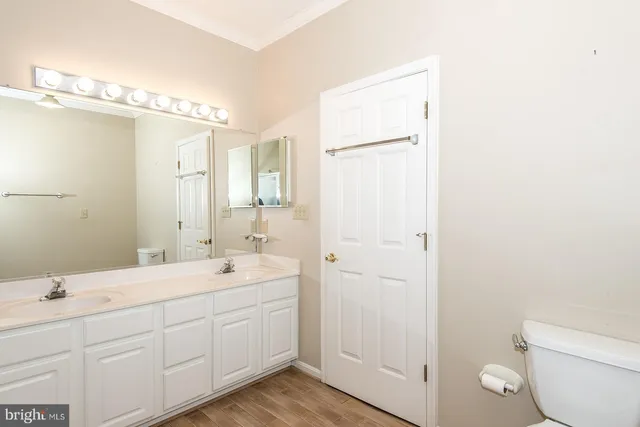 a spacious bathroom with a double vanity sink toilet and mirror