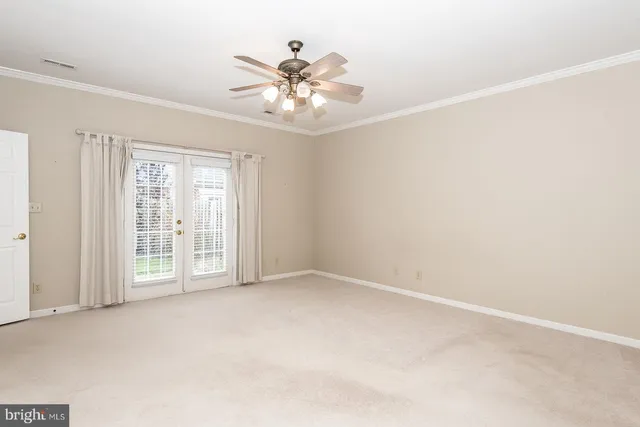 an empty room with chandelier fan and windows