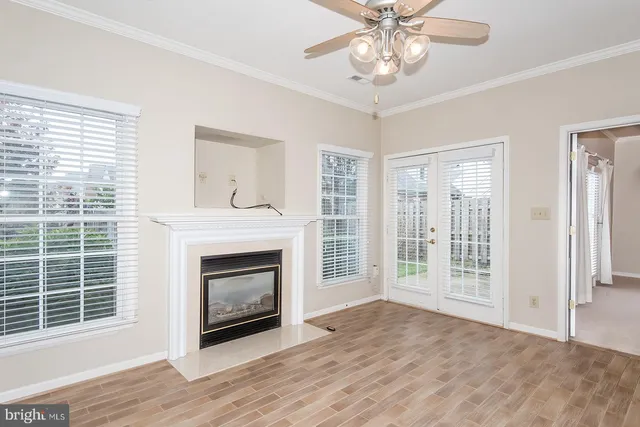 a view of an empty room with wooden floor fireplace and a window