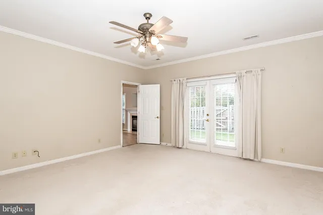 an empty room with windows and chandelier fan