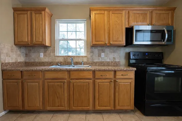 a kitchen with granite countertop a stove top oven microwave and cabinets