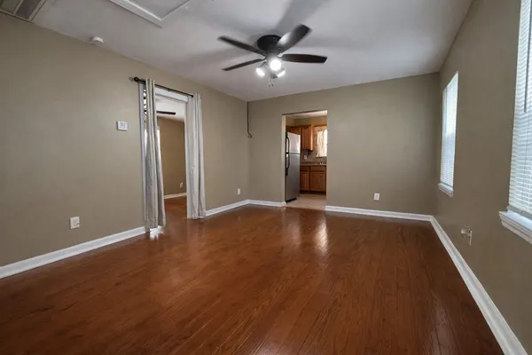 a view of an empty room with window and wooden floor