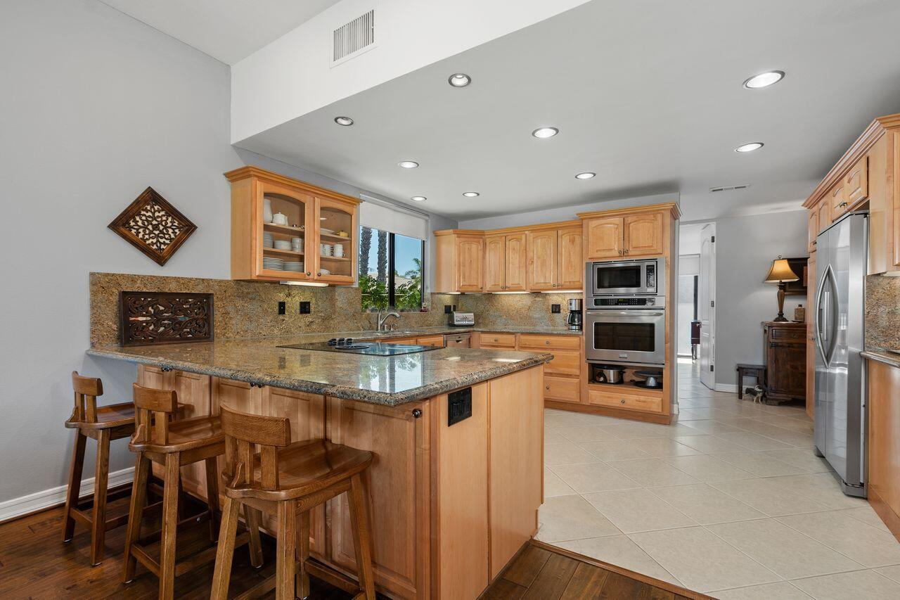 45475 Pueblo Road Indian Wells, CA 92210 - Photo 13 of 30 a kitchen with stainless steel appliances kitchen island granite countertop a table and chairs in it