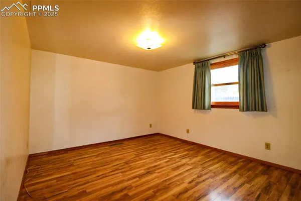a view of empty room with wooden floor