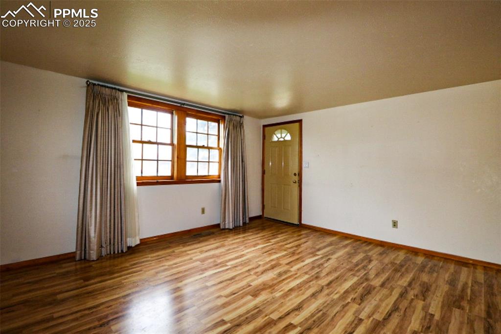 1206 Hartford Street Colorado Springs, CO 80906 - Photo 4 of 24 an empty room with wooden floor and windows