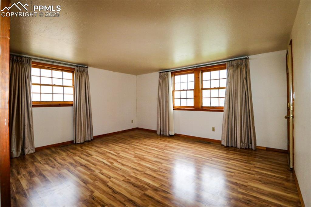 1206 Hartford Street Colorado Springs, CO 80906 - Photo 5 of 24 an empty room with wooden floor and windows