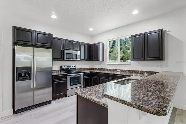 a kitchen with stainless steel appliances granite countertop a refrigerator a sink a stove a microwave and island