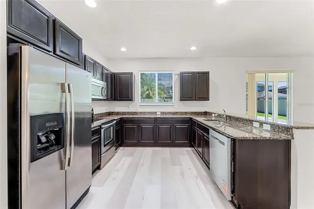 a kitchen with stainless steel appliances granite countertop a stove a sink and a refrigerator