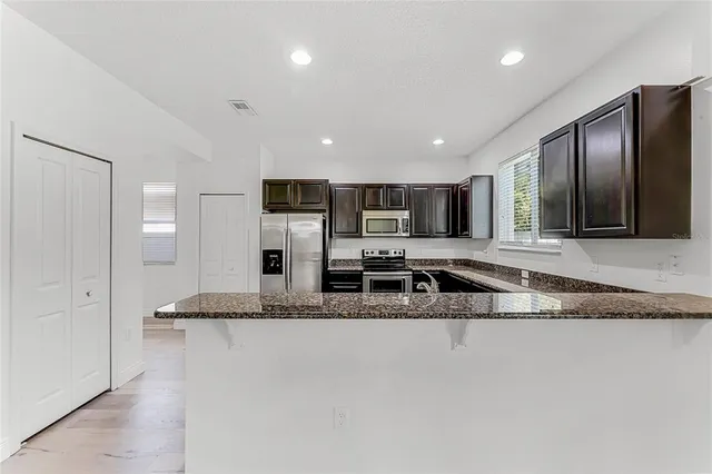 a large kitchen with granite countertop a refrigerator and a sink