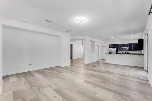 a view of kitchen with refrigerator and white cabinets